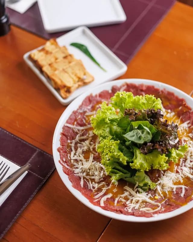 Carpaccio com folhas e queijo servido no ¡Vení! Parrilla