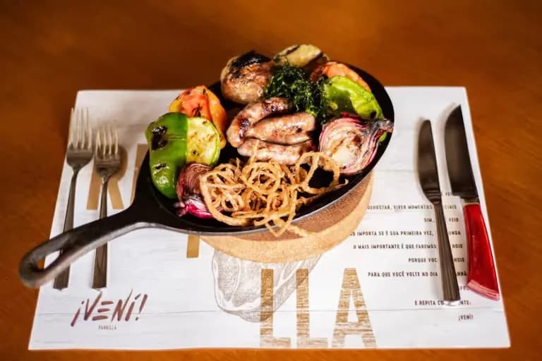 Linguiça de cordeiro grelhada com legumes no ¡Vení! Parrilla